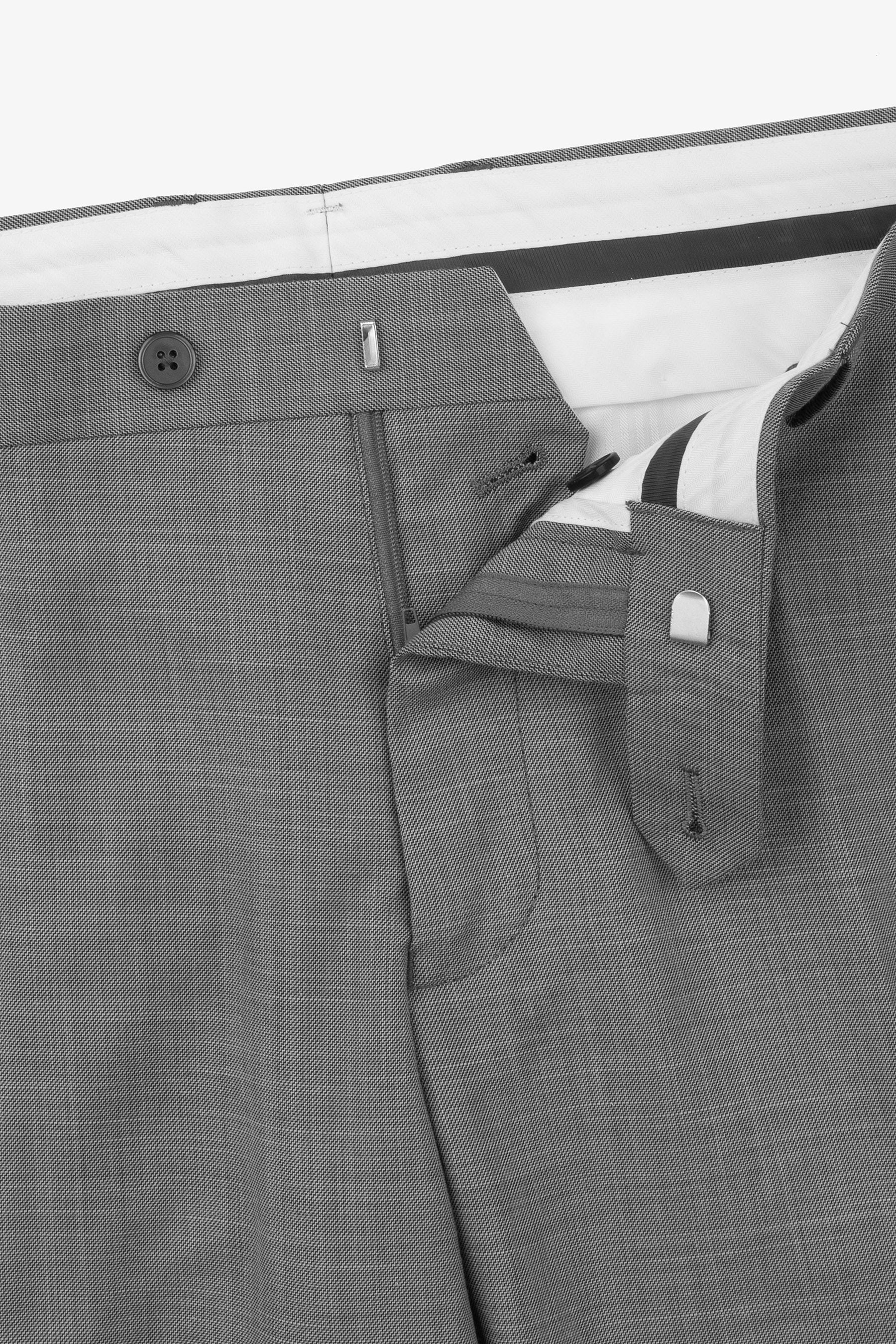 Gray pants with a flat front, partially unzipped fly, dark button, silver-toned hook-and-bar, and an inner silver-toned clasp
