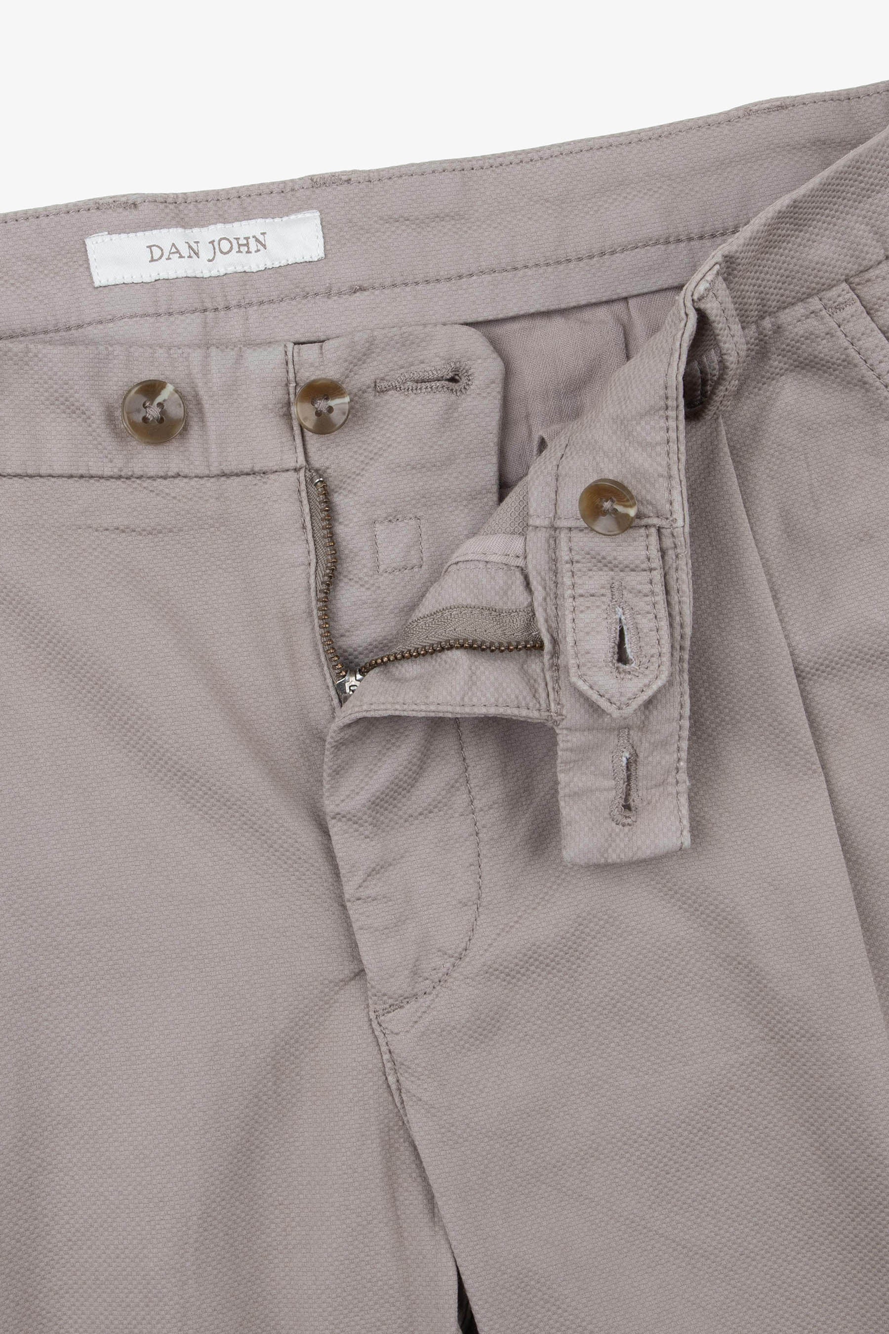 Tortora-colored trousers with a textured fabric, featuring a button and zipper fly closure, brown marbled buttons, and a "DAN