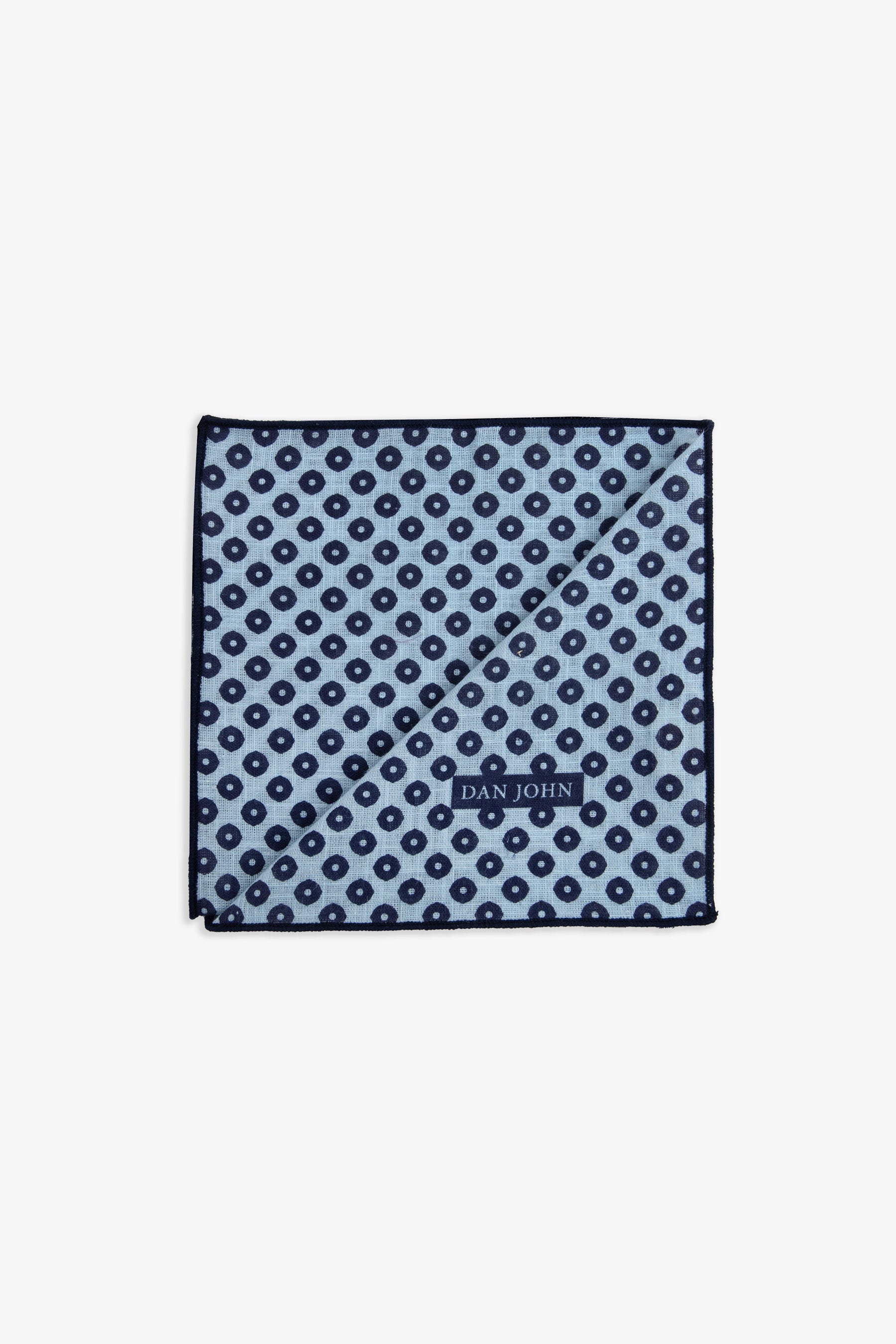 Light blue handkerchief with a repeating dark blue circle and dot pattern, dark blue stitched hem, and a 'DAN JOHN' label.