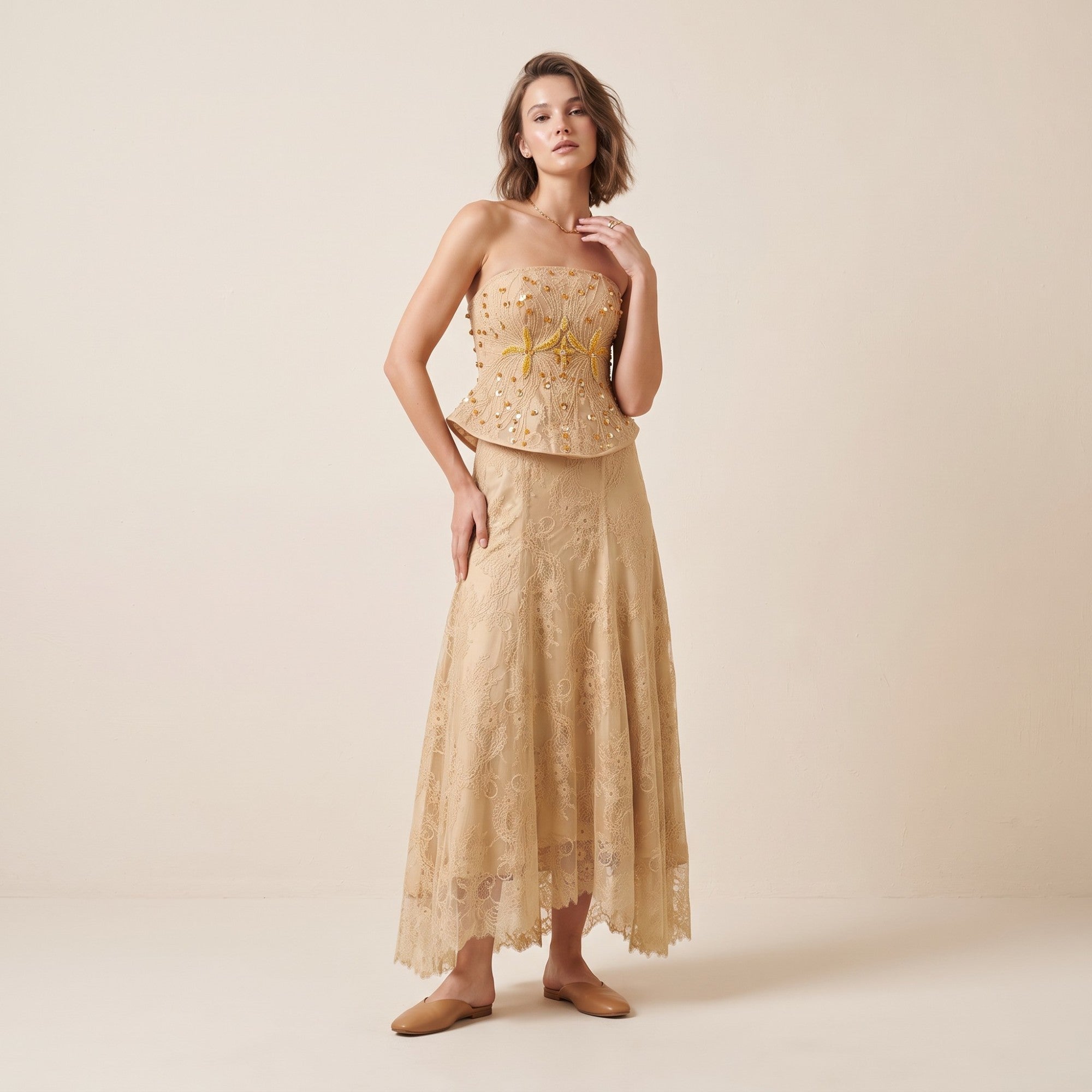 Beige strapless peplum top with gold-toned beaded and sequined embellishments, and a matching lace maxi skirt with a scallope