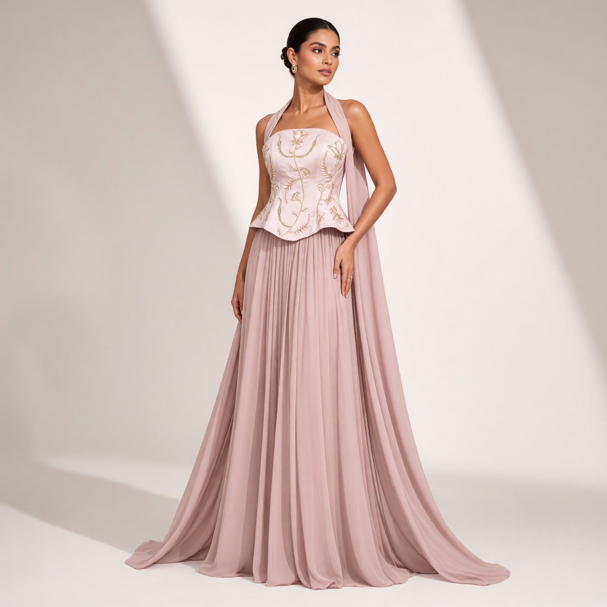 Mouve dress featuring a strapless peplum top with gold-toned floral embroidery, a flowing pleated skirt, and a matching drape