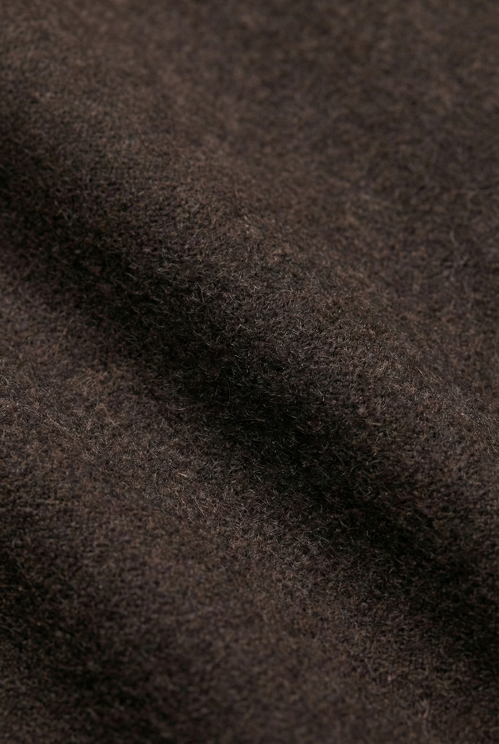 Close-up of dark brown jacket fabric with a soft, fuzzy texture and subtle folds.