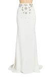 Front studio shot of a model wearing a floor-sweeping Zuhair Murad white cady maxi skirt, showcasing its high-rise waist and intricate silver crystal floral embellishments across the upper hips against a light grey background.