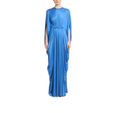 A woman modeling a floor-length royal blue gown with draped sleeves and a matching waist tie, shown against a plain white background.