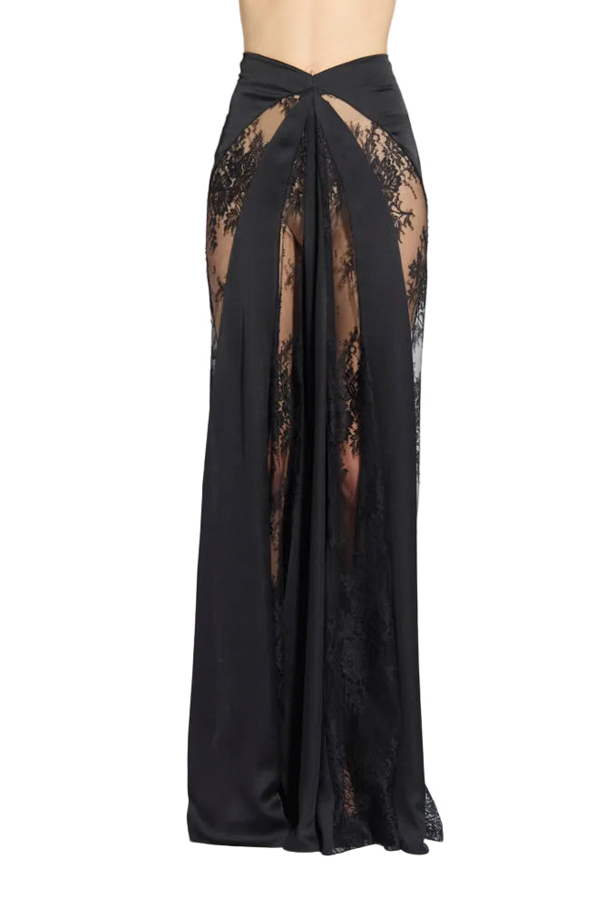 Front studio shot of a model wearing a floor-length Zuhair Murad black maxi skirt, highlighting its high-rise waist and structured panels mixed with sheer floral lace, set against a light grey background.