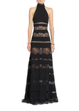 Front studio shot of a model wearing a floor-length Zuhair Murad black halter dress featuring a high collar and sheer horizontal floral lace paneling, set against a light grey background.