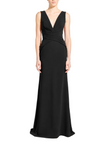 A blonde model wearing a sleeveless black floor-length gown with a deep V-neckline and gathered waist detail, standing against a light gray studio background.
