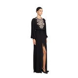 Three-quarter studio portrait of a model showcasing the high front slit, flowing silhouette, and intricate crystal-embellished bodice of the black Zuhair Murad bishop sleeve gown.