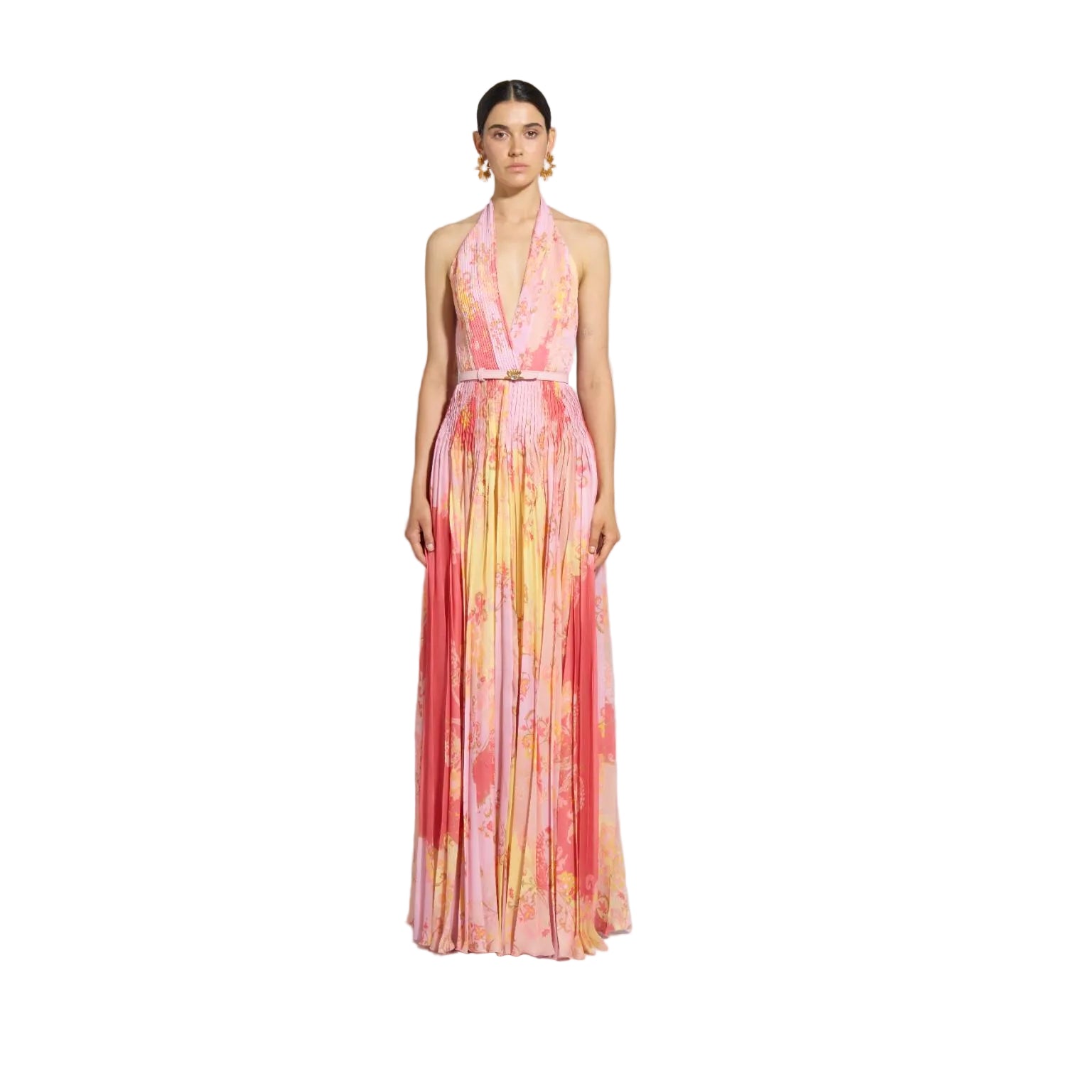 Front studio portrait of a model wearing a vibrant pink and yellow pleated Zuhair Murad halter neck gown with a plunging neckline and a thin pink belt.