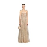 Front studio portrait of a model showcasing the floor-length, shimmering champagne gold Zuhair Murad strapless tulle evening gown while carrying a small beige top-handle bag, available at the BLUE SALON.