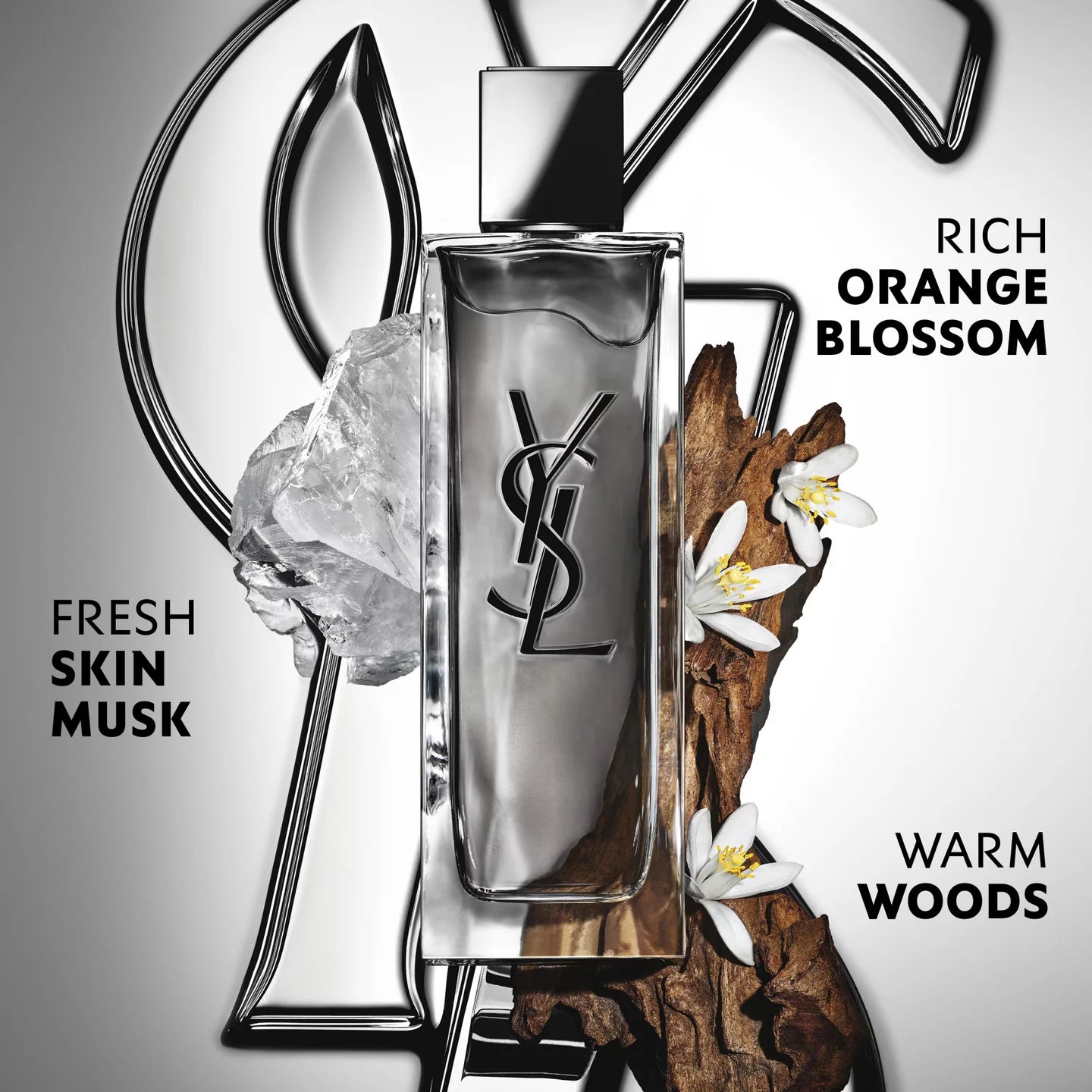 Clear glass rectangular perfume bottle with a silver-toned back panel, black YSL logo, and a shiny silver-toned block cap.