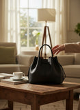 Blue Salon Florin black pebbled cowhide leather medium satchel bag with drawstring closure and gold hardware.