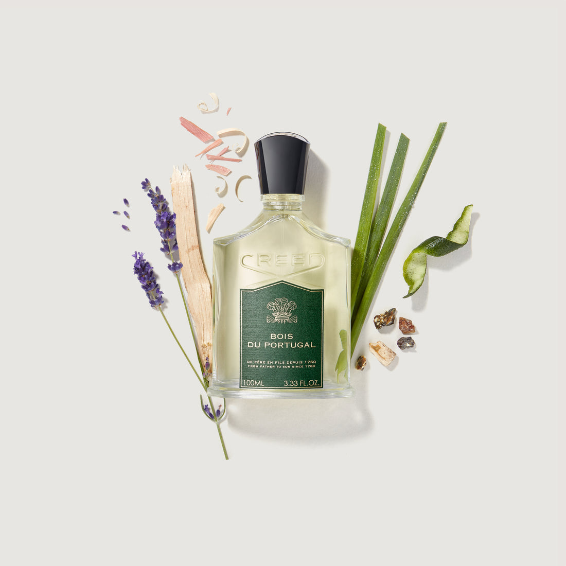Clear glass perfume bottle with light yellow liquid, a black cap, and a green label with 'CREED BOIS DU PORTUGAL'.