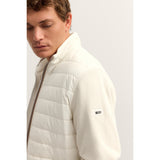 Ecru jacket with a padded, quilted front and knitted sleeves. Features a stand-up collar and a brown-toned full zipper.