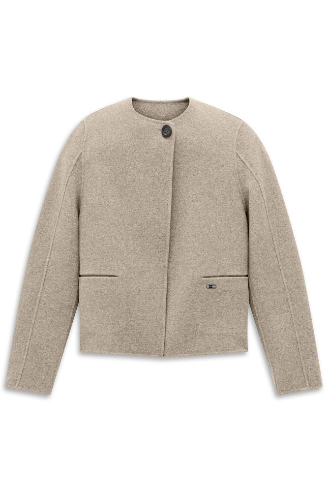 Beige collarless jacket with a single dark button closure, two horizontal welt pockets, and a small metallic logo plaque.