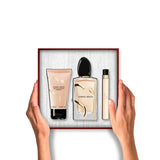A Giorgio Armani Si gift set: a peach body lotion tube, a clear perfume bottle with gold-toned wavy accents, and a peach Si t