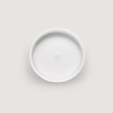 Top view of a white, circular candle with a smooth surface and a slight central indentation.