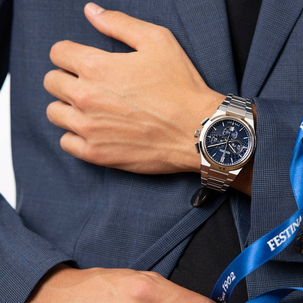Silver-toned chronograph watch with a dark blue dial, three subdials, gold-toned ridged bezel, and a silver-toned metal link