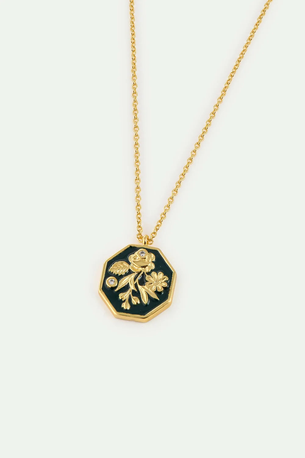Gold-toned necklace with an octagonal dark green enamel pendant featuring raised gold-toned floral designs and two small clea