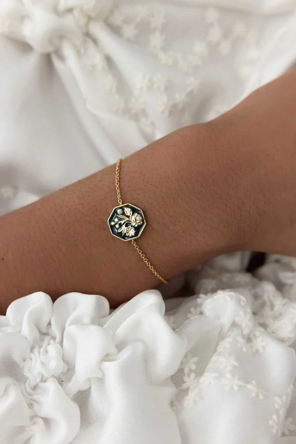 Gold-toned chain bracelet with an octagonal dark green enamel pendant featuring a gold-toned floral design and two clear acce
