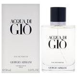 White rectangular box and clear glass perfume bottle with black cap, silver-toned band, and black text.