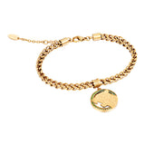 Gold-toned woven chain bracelet with a circular gold-toned charm featuring a tiger head design and green stones.