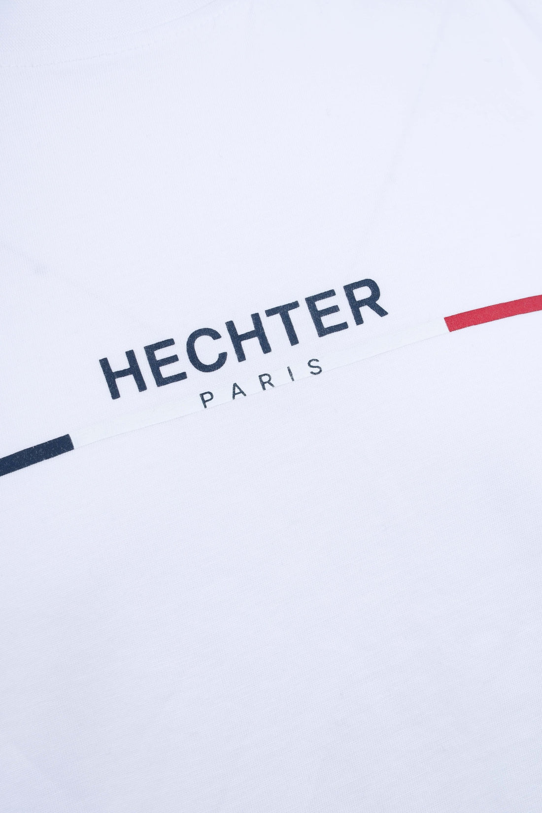 White t-shirt featuring a diagonal graphic with black 'HECHTER PARIS' text above a thin black, white, and red stripe.