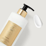 White opaque bottle with a black pump dispenser and gold-toned collar. A gold-toned label with a crest and "CREED AVENTUS" te