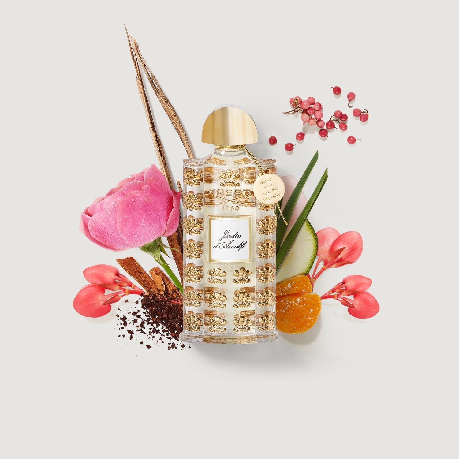 Clear perfume bottle with a gold-toned dome cap and a hanging tag. It features a repeated gold-toned crown pattern and a whit