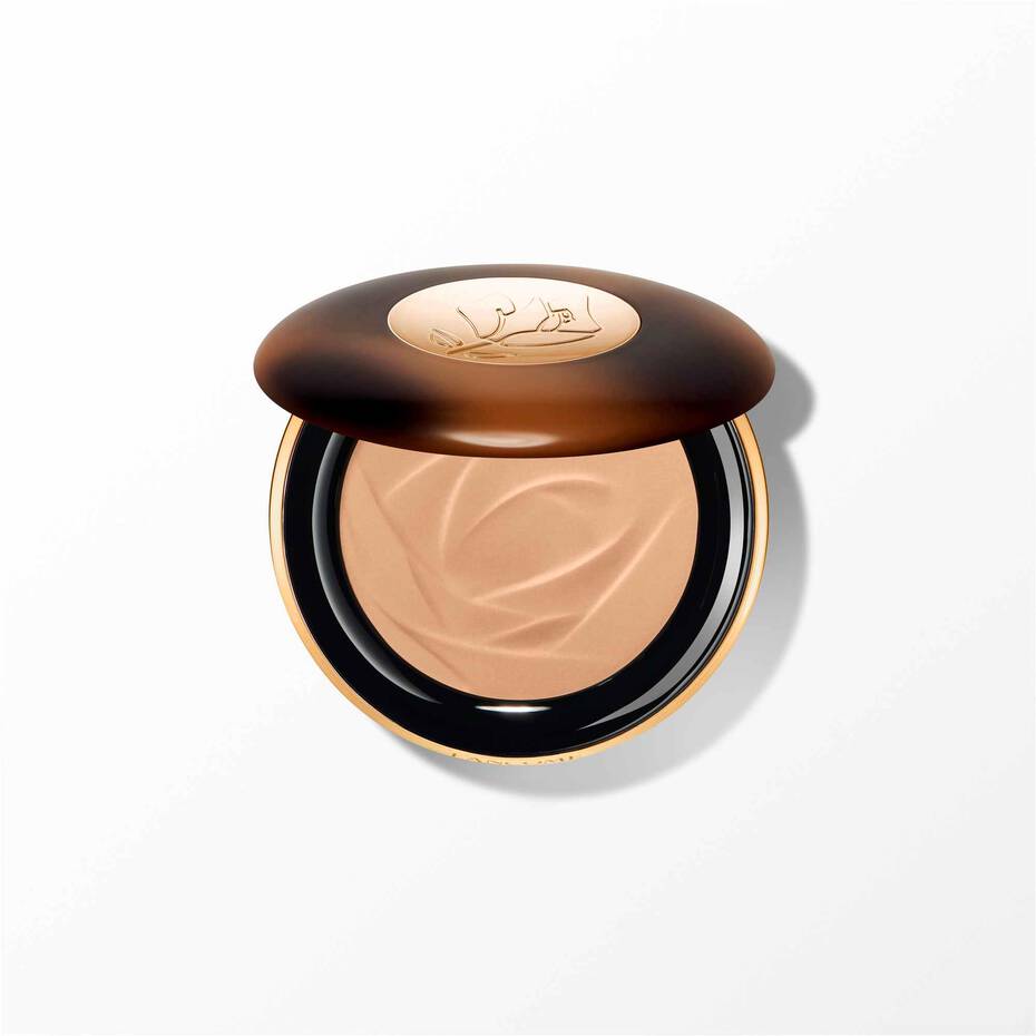 Lancome powder bronzer compact with a dark tortoiseshell-effect lid, gold-toned rim, and light bronze powder with a wave patt