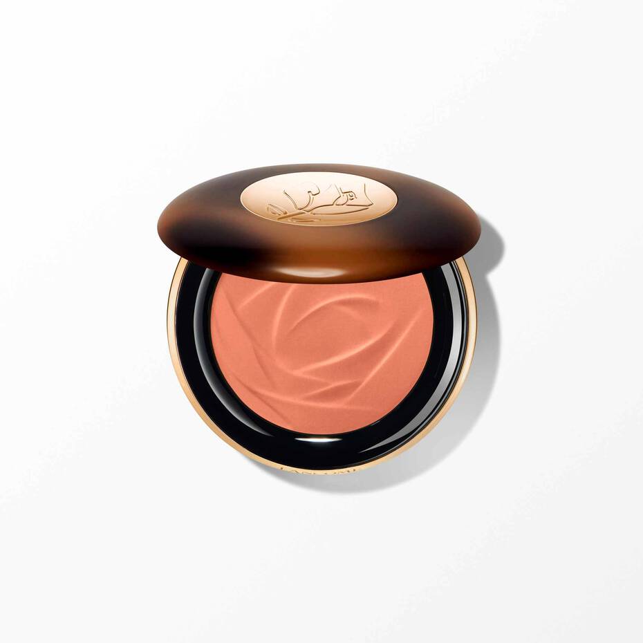Lancome powder bronzer compact with a dark brown lid, gold-toned accents, and peachy-orange powder with a sculpted rose desig