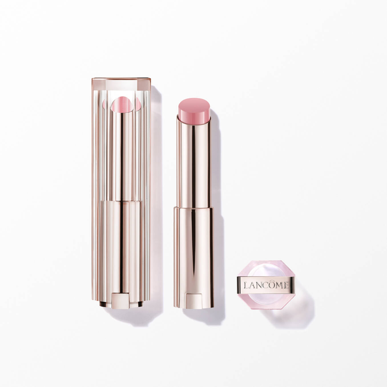 Light pink lipstick in a gold-toned, ribbed tube with a clear, ridged cap. A small, hexagonal pink container with 'LANCOME'.