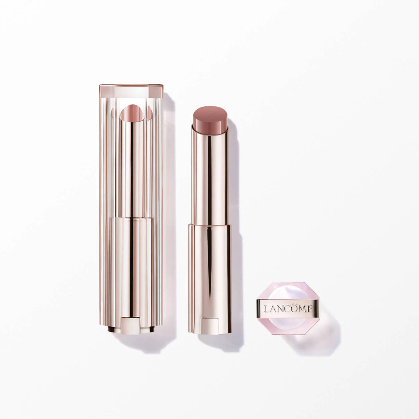 Rose gold-toned lipstick with a light brown bullet, a clear ribbed cap, and a light pink hexagonal piece with 'LANCÔME'.