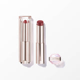 Rose gold-toned lipstick with dark rose bullet, one open, one in clear ribbed case. Small hexagonal pink container with Lancô
