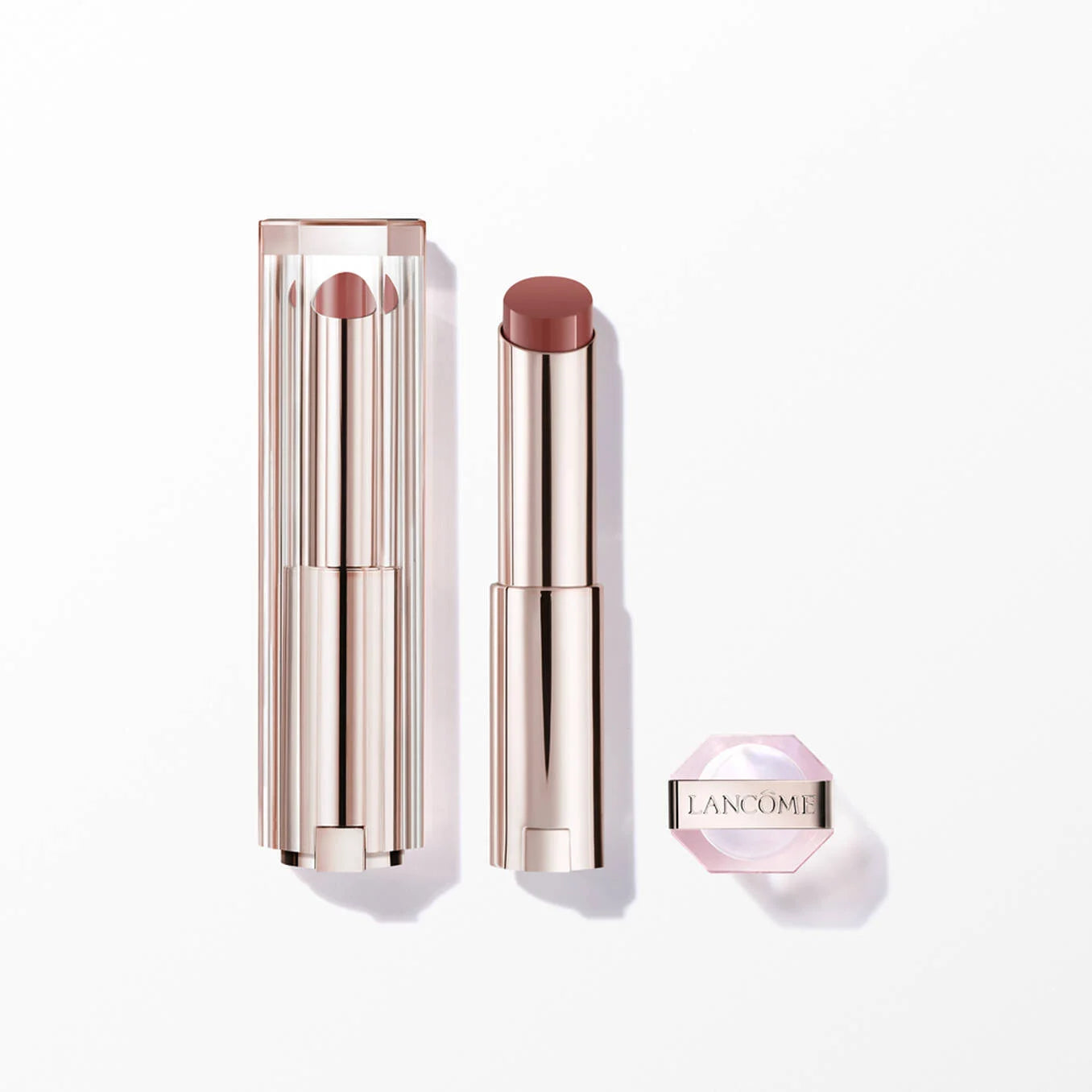 Rose gold-toned lipstick with clear ribbed cap, brown-pink bullet, and a separate small light pink hexagonal container.