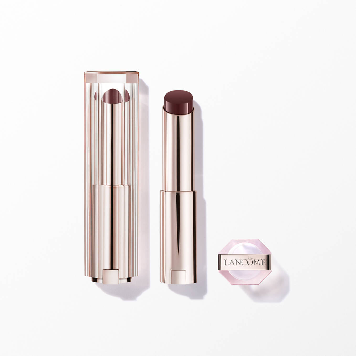 Lancome Lip Idole lipstick: clear ribbed cap, rose gold-toned base, dark plum bullet. Small pink hexagonal pot with Lancome l