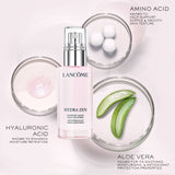 Cylindrical clear glass bottle of Lancome Hydra Zen liquid moisturizer with pink liquid and a silver-toned pump dispenser.