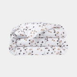 Folded white duvet cover and pillow case set featuring a repeating pattern of small brown and beige botanical motifs.