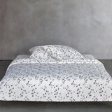 Beige duvet cover and pillow case set with a repeating pattern of small, stylized plant sprigs in dark brown and light brown.