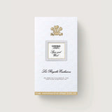 White rectangular box with embossed pattern, gold-toned crest, silver-toned frame with 'Creed Spice and Wood', and gold-toned
