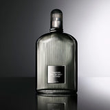 Dark grey fluted glass fragrance bottle with a black label and silver-toned border, topped with a ribbed black cap.