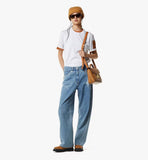 Person wearing a white t-shirt, blue jeans, brown hat, and sunglasses, holding a brown leather bag on a white background.
