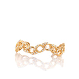 Gold-toned wave chain cuff bracelet with a textured finish and numerous clear handset stones.