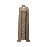 Front view of brown high-neck embroidered evening gown with attached floor-length cape sleeves and floral detailing.
