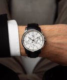 Silver-toned watch with a white textured dial, silver-toned hands, three subdials, and a black textured leather strap.