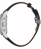 Side view of a watch with a silver-toned case, crown, and pushers. It has a black textured leather band with a silver-toned d